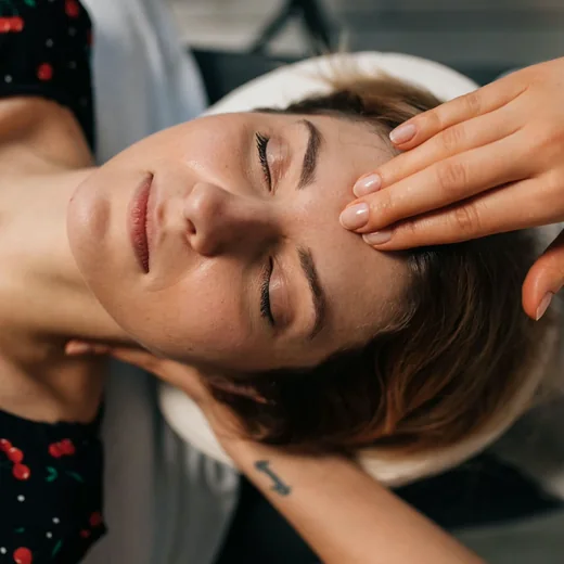 A practitioner’s hands resting gently either side of a client’s head