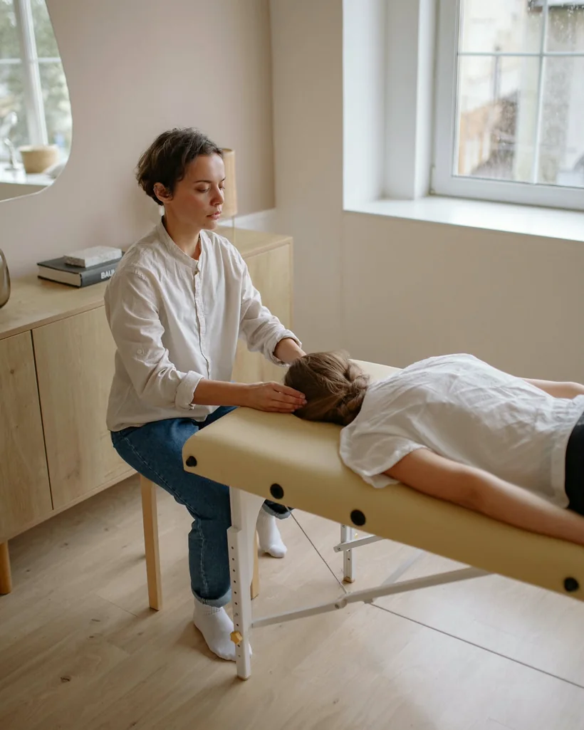 A practitioner beside a treatment table in a bright, calm studio